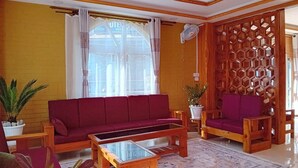 Una sala de estar con un sofá rojo, una mesa de centro de madera y un separador decorativo de madera.