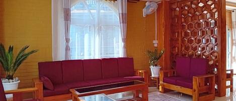 A living room with a red sofa, a wooden coffee table, and a decorative wooden partition.