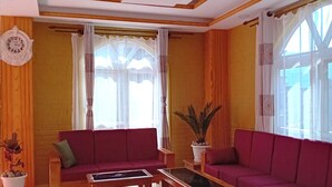 Una sala de estar con dos sofás rojos, una mesa de centro y una planta en maceta.