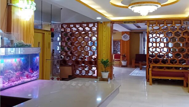 Un área de recepción con mostrador, un acuario, un letrero de recepción y un panel de madera decorativo.