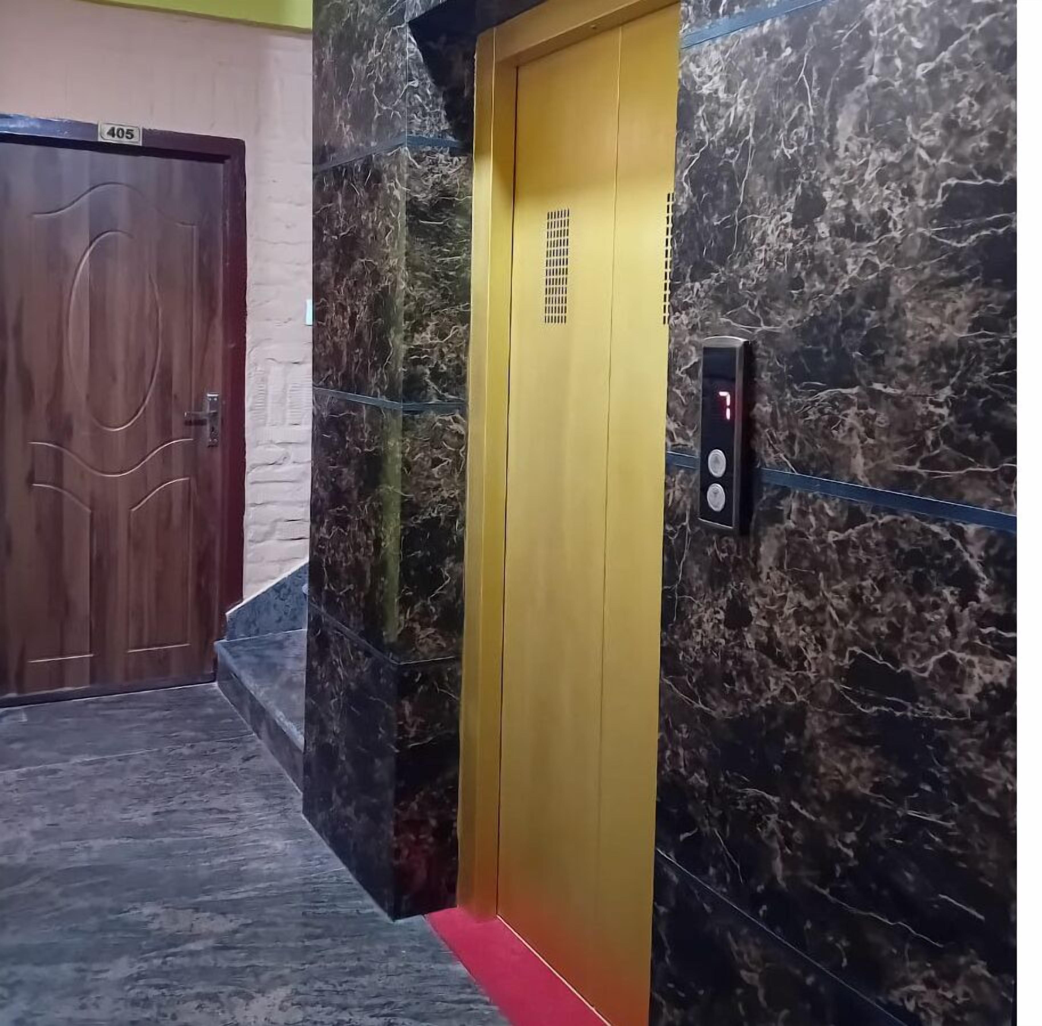 An elevator with a marble wall and a wooden door.