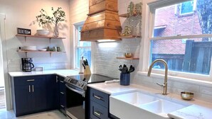 Een moderne keuken met donkere kastjes, een wit aanrecht, een roestvrijstalen spoelbak en een inbouwoven.