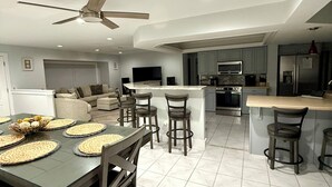 A modern kitchen with a central island, bar stools, and a dining table set for six. - St. Pete - Clearwater Vacation Rental Heated Pool & Hot tub, Beach (Seminole)