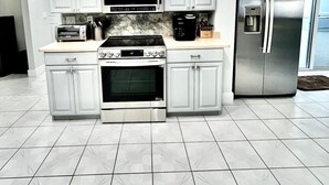 A modern kitchen with white cabinets, stainless steel appliances, a built-in oven, and a refrigerator. - St. Pete - Clearwater Vacation Rental Heated Pool & Hot tub, Beach (Seminole)