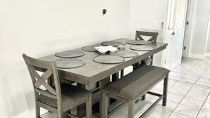 A dining area with a rectangular table, four chairs, and a bench. - St. Pete - Clearwater Vacation Rental Heated Pool & Hot tub, Beach (Seminole)