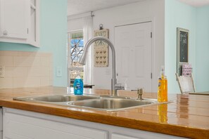 A kitchen with two stainless steel sinks, a wooden countertop, and a white cabinet.