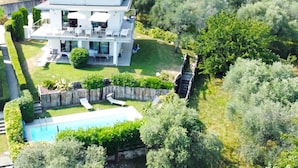 A modern two-story house with a swimming pool, surrounded by lush greenery and a well-maintained lawn. - Casa Oleandri Shared Pool & Lake View, Toscolano Maderno, Italy (Toscolano Maderno)