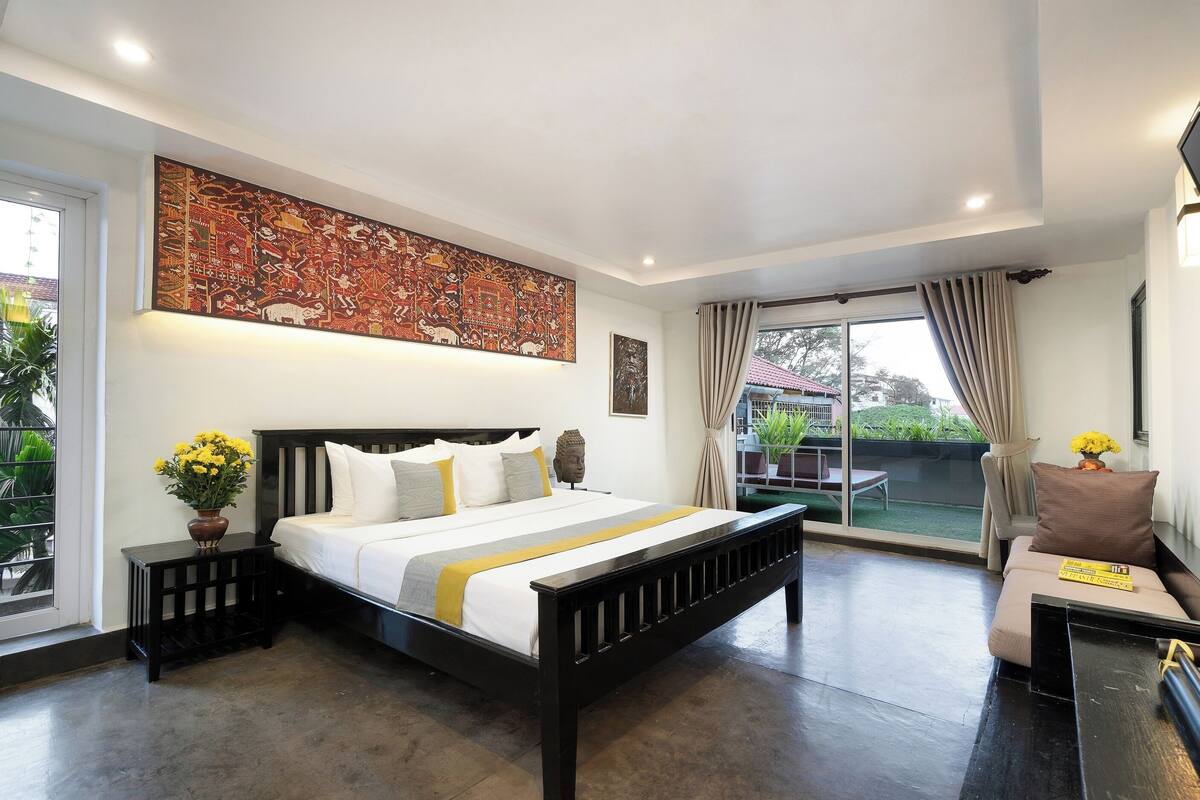 Een moderne slaapkamer met een groot bed, een flatscreen televisie, een klein tafeltje en een balkon met uitzicht.