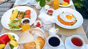 Una mesa servida con alimentos para el desayuno, como huevos, tostadas, fruta y bebidas.