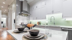 Een moderne keuken met witte kastjes, een roestvrijstalen afzuigkap en een lichtgroene spatwand.