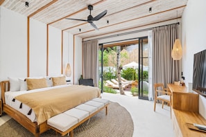 Quarto moderno com uma cama grande, uma escrivaninha e vista para área externa.
