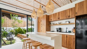 Une cuisine moderne avec des meubles en bois, un réfrigérateur noir et un coin bar équipé de tabourets.