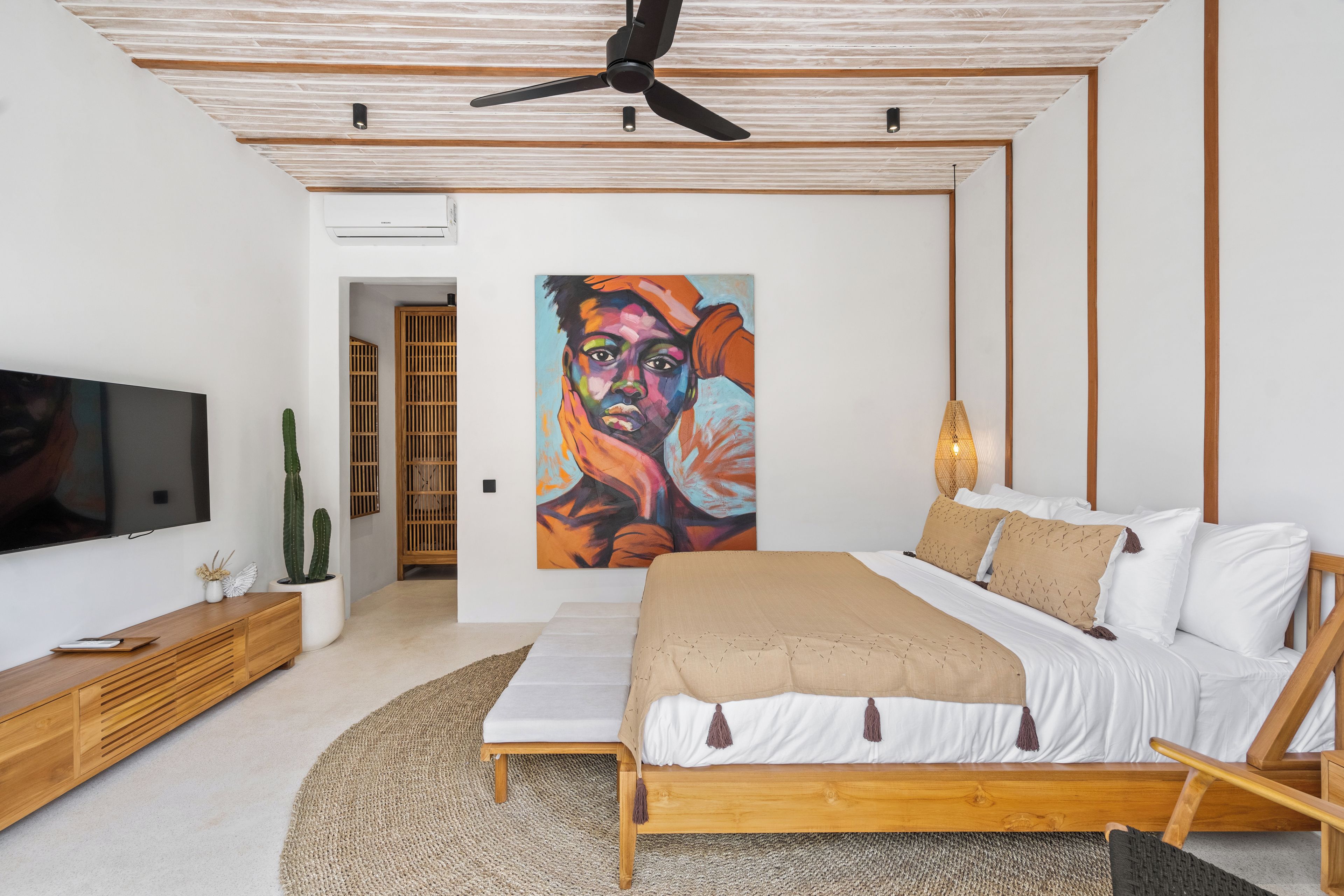 Un dormitorio moderno con cama, televisor, un cuadro y ventilador de techo.