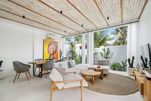 Uma sala de estar moderna com uma janela grande, um quadro e um cacto.