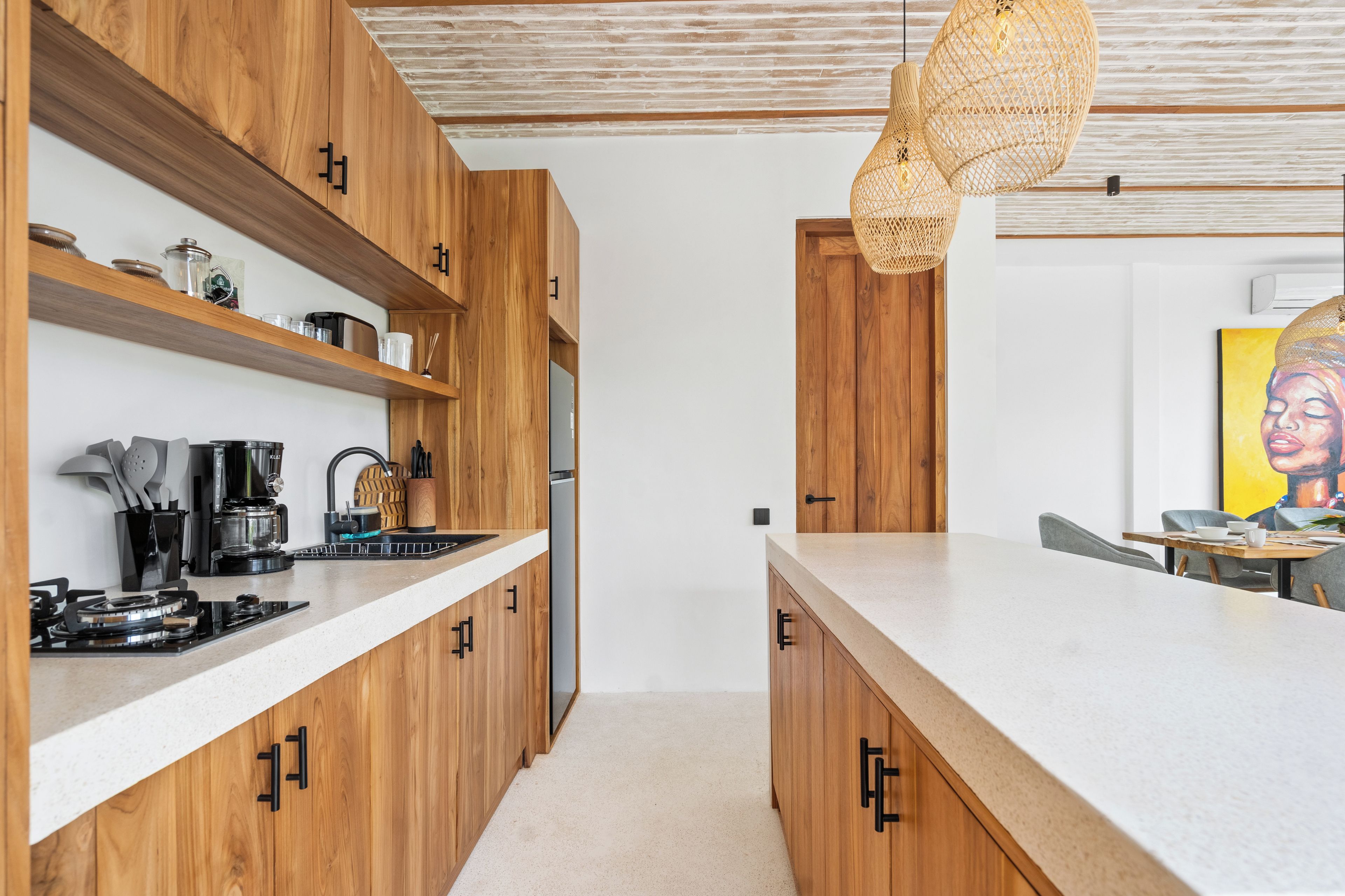 Cozinha moderna com armários de madeira, bancada branca e luminária pendente.