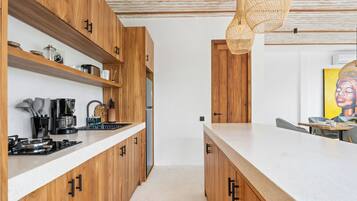 Una cocina moderna con armarios de madera, encimera blanca y una lámpara colgante.