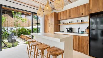 Una cocina moderna con armarios de madera, un refrigerador negro y una zona de bar con taburetes.