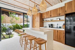 Cozinha moderna com armários de madeira, geladeira preta e um balcão com banquetas.