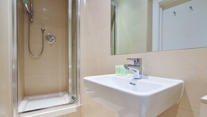 Ein Badezimmer mit Dusche, Waschbecken und Spiegel.
