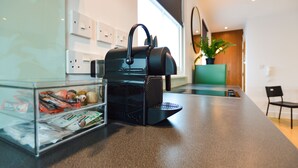 Eine moderne Küche mit einer Kaffeemaschine, einem Glasbehälter mit Snacks und einem Blumentopf.