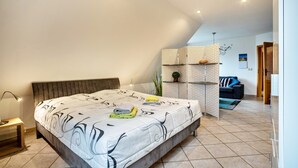 Une chambre avec un grand lit, une table de chevet, une armoire et une vue sur le salon.
