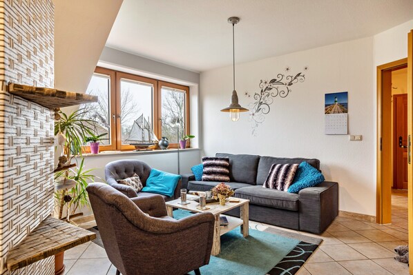 Una sala de estar con sofá, sillón, mesa de centro y decoración en la pared.