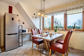 Una cocina equipada con refrigerador, microondas y mesa de comedor con sillas.