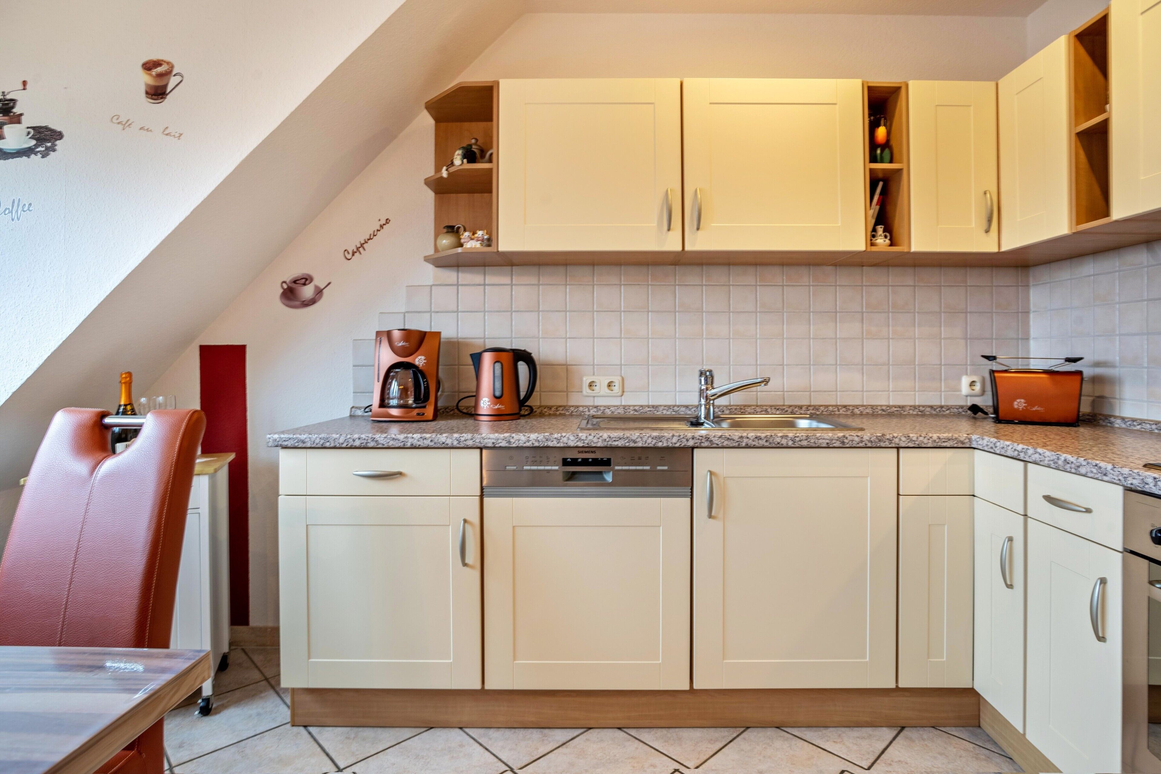 A kitchen with light-colored cabinets, a coffee maker, and a kettle.