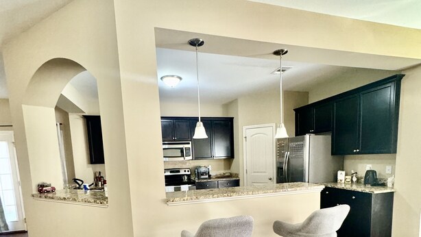 A modern kitchen with dark cabinets, a central island, and two bar stools.