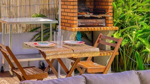 An outdoor dining area with a brick oven, wicker furniture, and a thatched roof. - Villa Idylle (ST LOUIS)