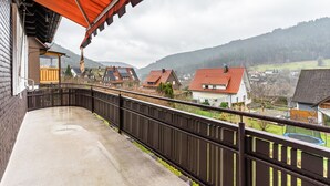 Un balcon donnant sur un quartier résidentiel, une clôture en bois et des maisons aux toits rouges.
