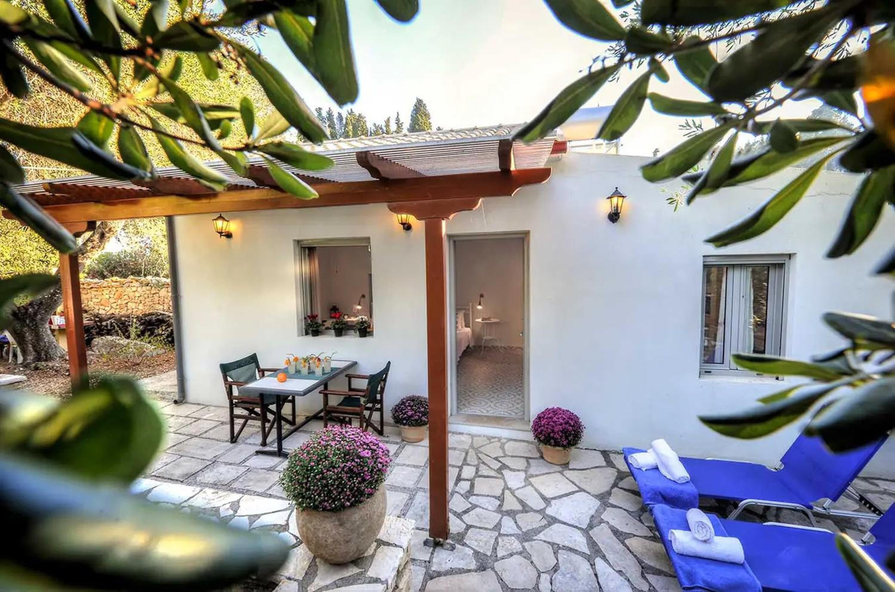 Un patio con pérgola, mobiliario exterior y plantas en macetas.