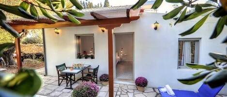 Un patio con pérgola, mobiliario exterior y plantas en macetas.
