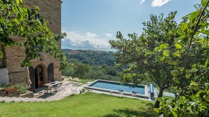 Ein Poolbereich mit Blick auf die Landschaft, ein Backsteinhaus und Sitzmöglichkeiten im Freien.