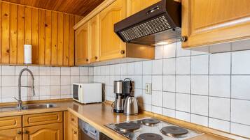 A kitchen with wooden cabinets, a stainless steel sink, a microwave, a coffee maker, and a stove.