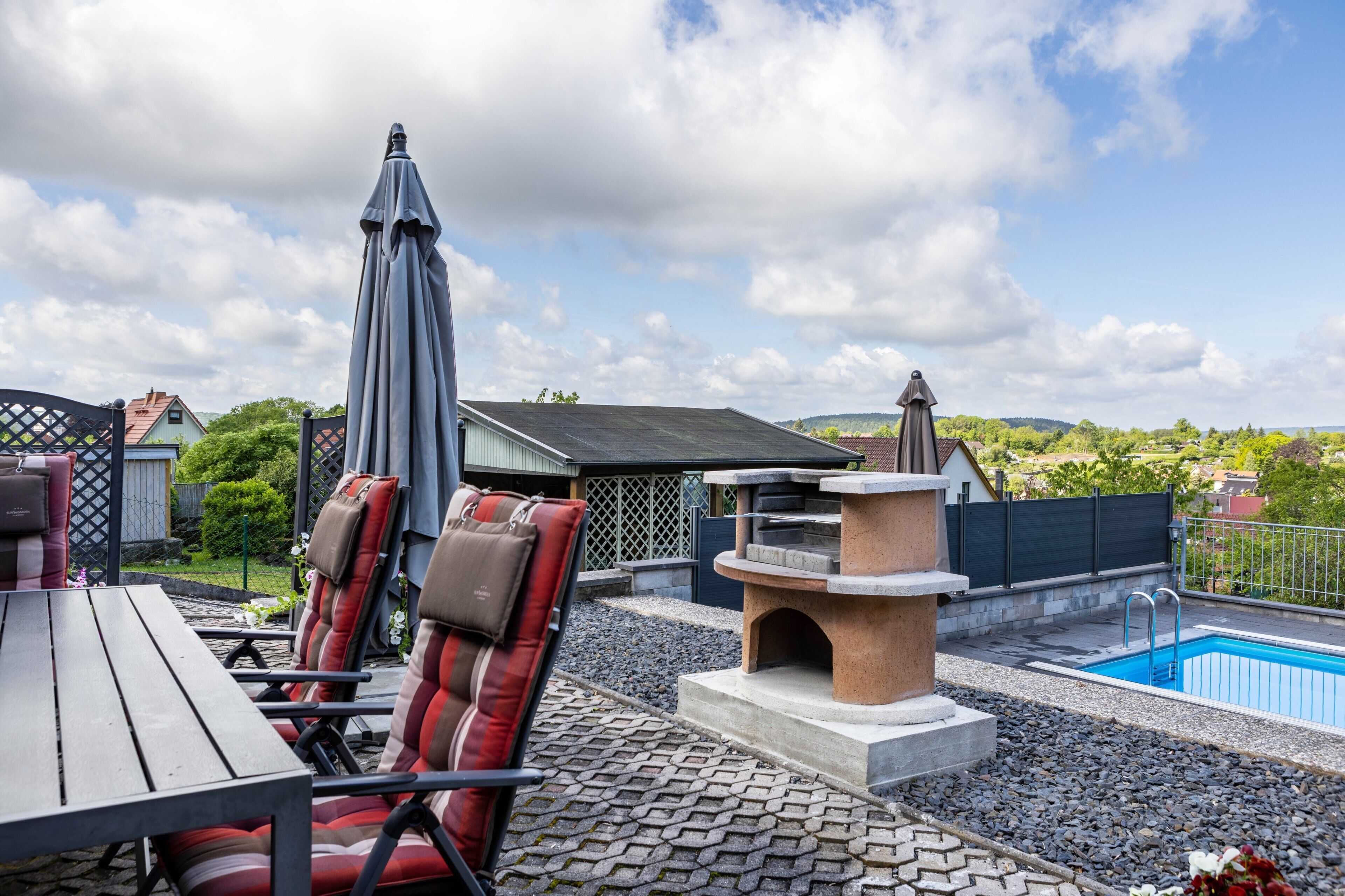 A rooftop patio with outdoor seating, a pool, and a stone fireplace.
