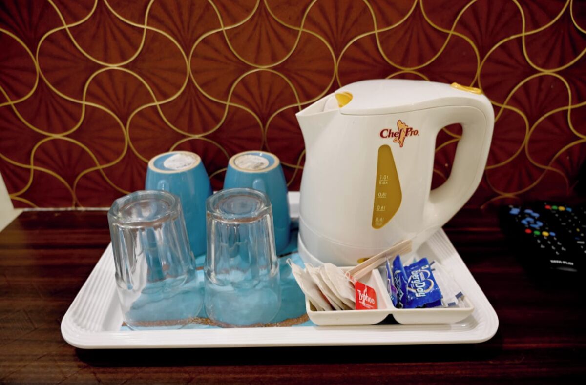 A tray with a coffee maker, glasses, and tea packets.