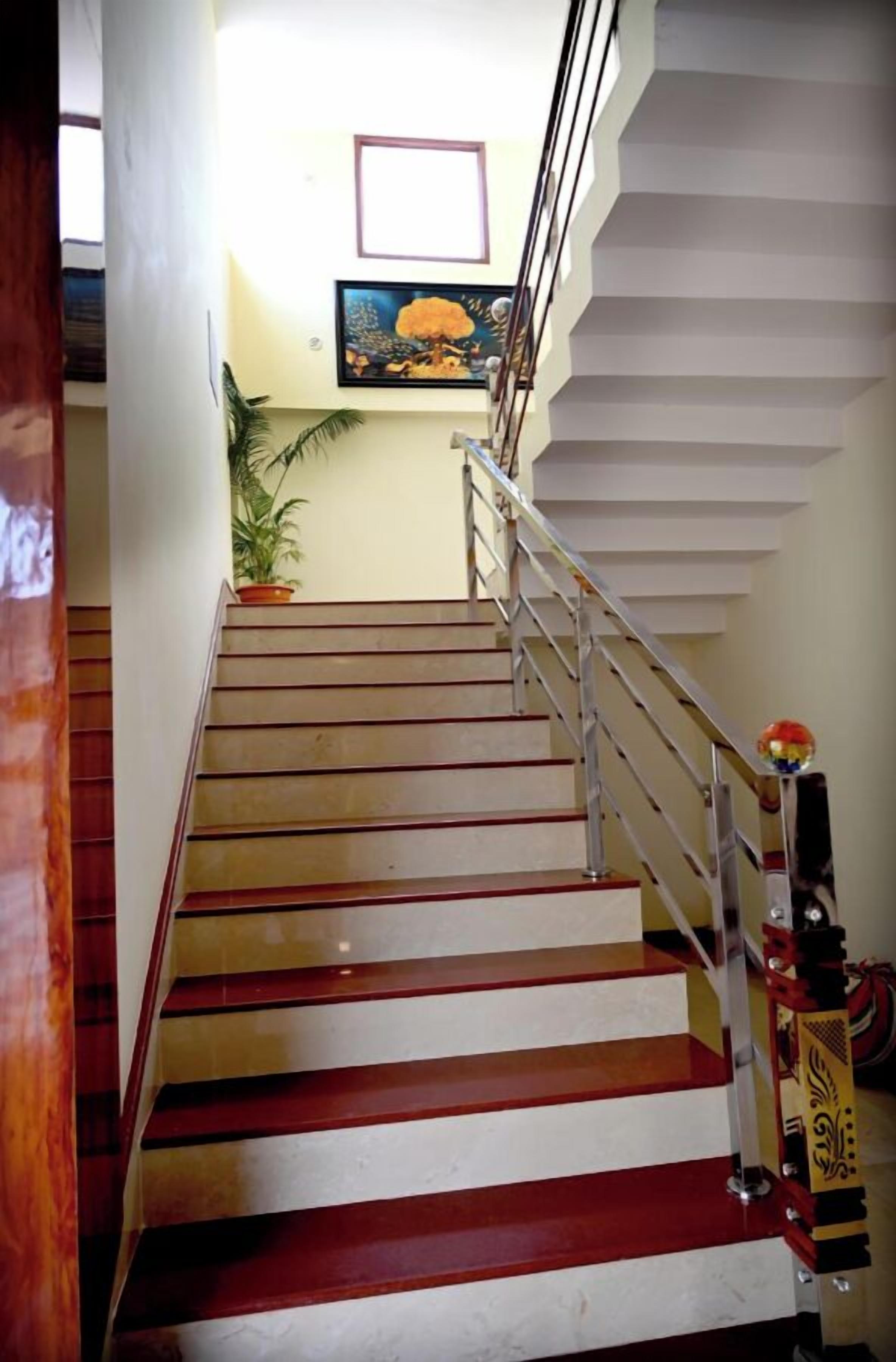 A staircase with alternating red and white steps, metal handrails, and a potted plant at the top.