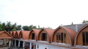 A row of wooden-roofed cabins with a pool in the foreground. - The Garuda Hostel & Accomodation (Penida Island)