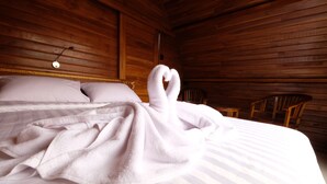 A wooden cabin room with a bed, pillows, and a heart-shaped towel on the bed. - The Garuda Hostel & Accomodation (Penida Island)