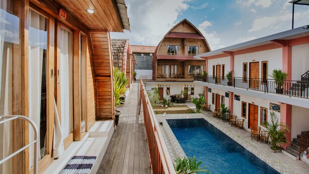 A wooden building with a pool, balconies, and outdoor seating. - The Garuda Hostel & Accomodation (Penida Island)