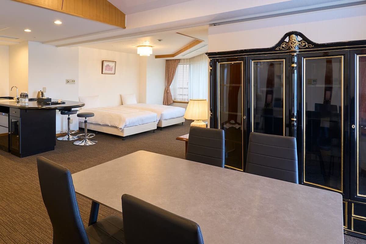Une chambre d’hôtel équipée d’une table à manger, de deux lits, d’une armoire et d’une petite kitchenette.