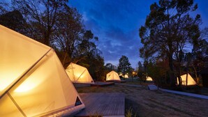 A row of illuminated tents in a campsite with a wooden deck in the foreground. - Sport & Do Resort  RESOL NO MORI (Nagara)