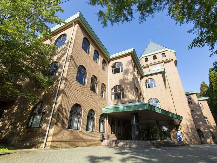 A large, multi-story building with a prominent tower and arched windows.