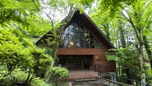 A wooden cabin with a steep roof, surrounded by dense green foliage. - Sport & Do Resort  RESOL NO MORI (Nagara)
