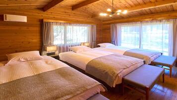 Een kamer in chaletstijl met vier bedden, houten wanden en grote ramen voorzien van gordijnen.