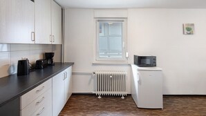 Una cocina compacta con gabinetes blancos, un microondas integrado y una ventana.