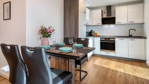 A modern kitchen with white cabinets, a wooden dining table, and black chairs.