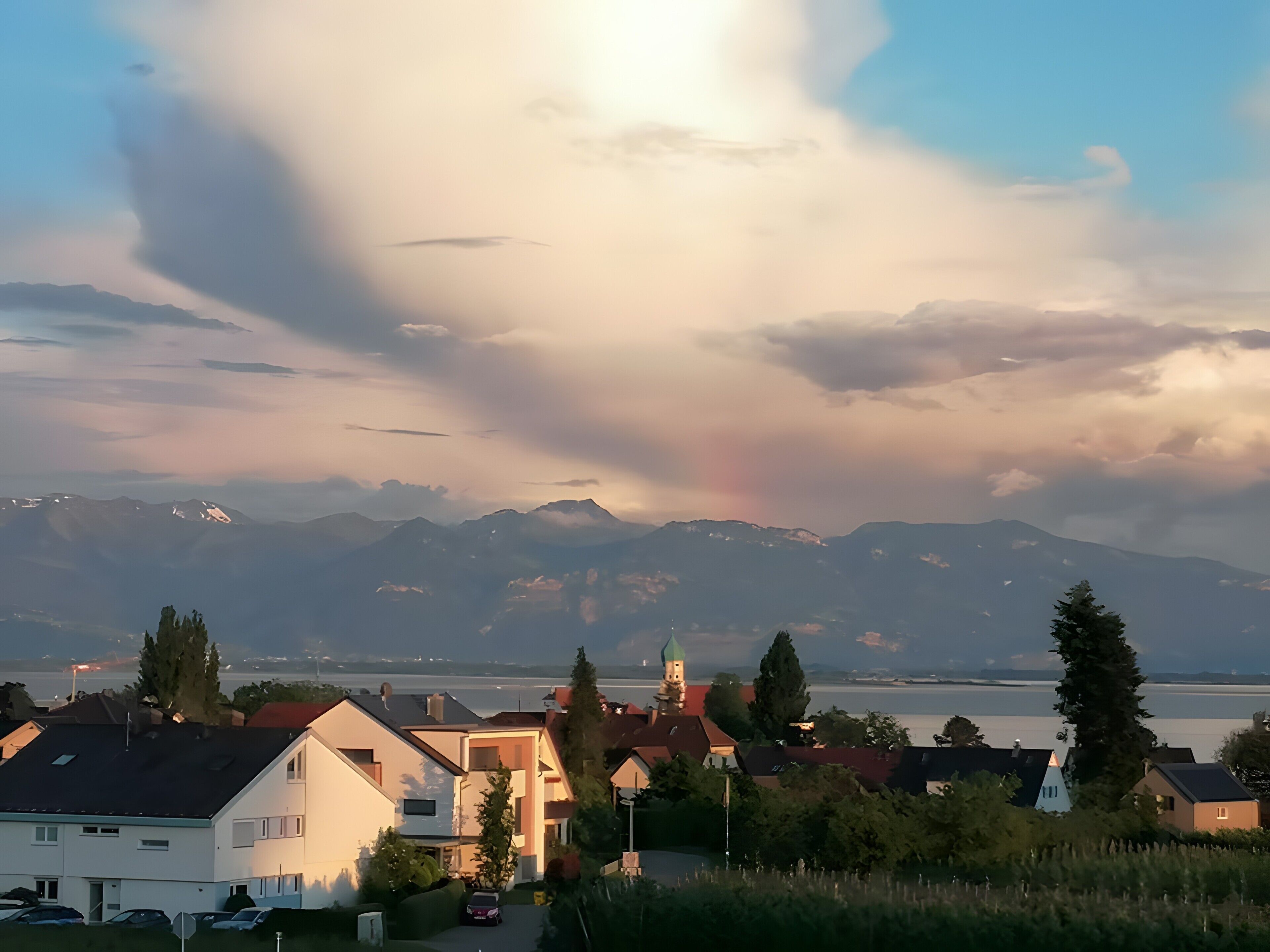 Ein Wohngebiet mit Häusern, einer Kirche und Bergen im Hintergrund.