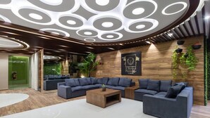 A modern lounge area with a sectional sofa, a coffee table, and a decorative ceiling with circular patterns. - Stylish Studio in Playa del Carmen with Rooftop Pool Walk to Beach & 5th Avenue (Playa del Carmen)
